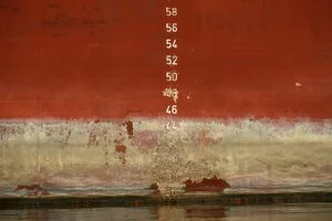 Draft numbers painted on a red ship's hull just above the waterline.