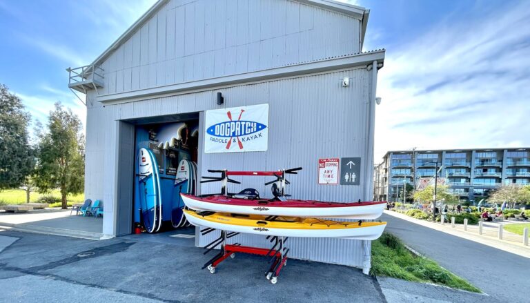 The Dogpatch Paddle shop at Crane Cove, two kayaks racked outside the open roller door.