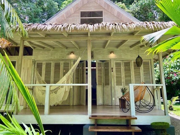 A thatched timber cabin with a hammock slung across its porch.