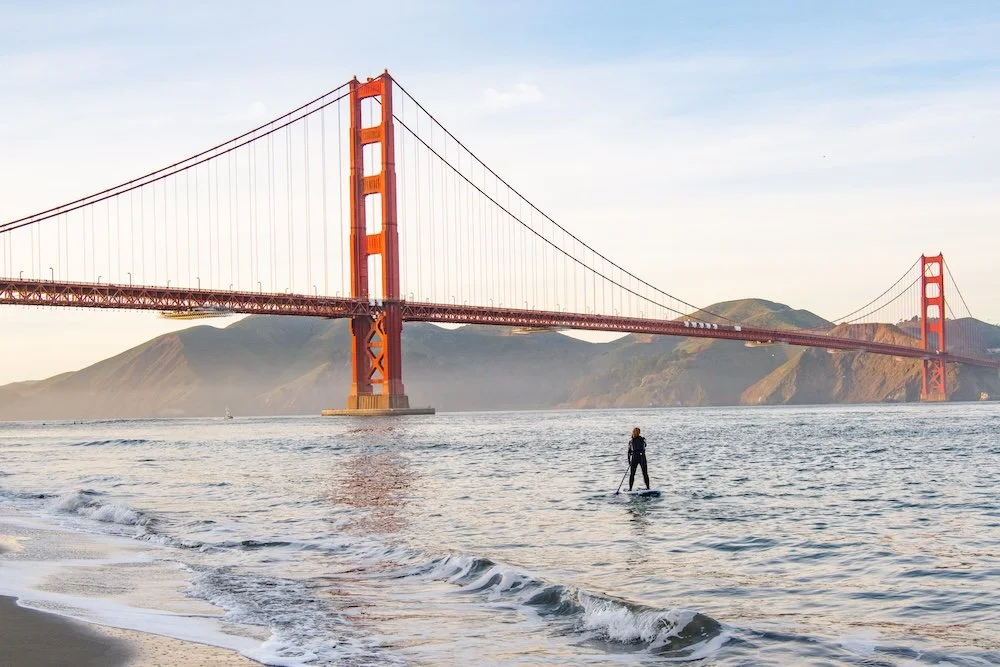 A lone paddler on the water with the Golden Gate Bridge behind.