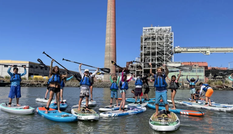 A group of campers on paddleboards near the old power station chimney.