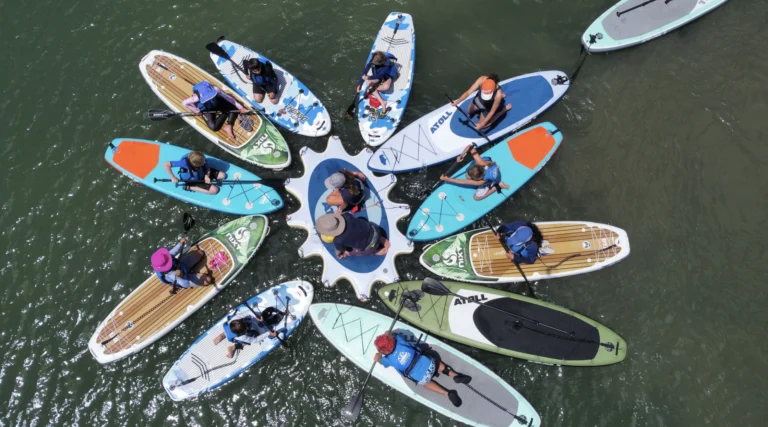Paddleboards seen from above, arranged in a circle on the water.
