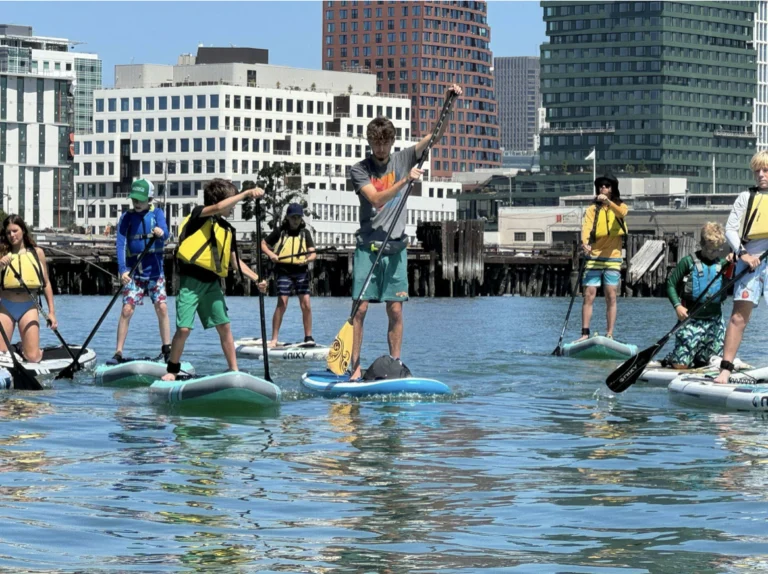 A group on paddleboards with the downtown buildings behind them.