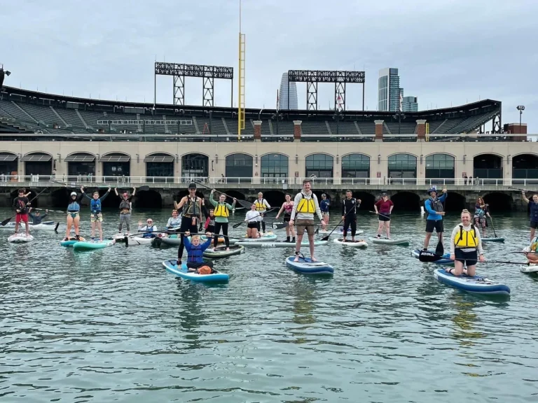 A line of paddlers on the water in front of Oracle Park.