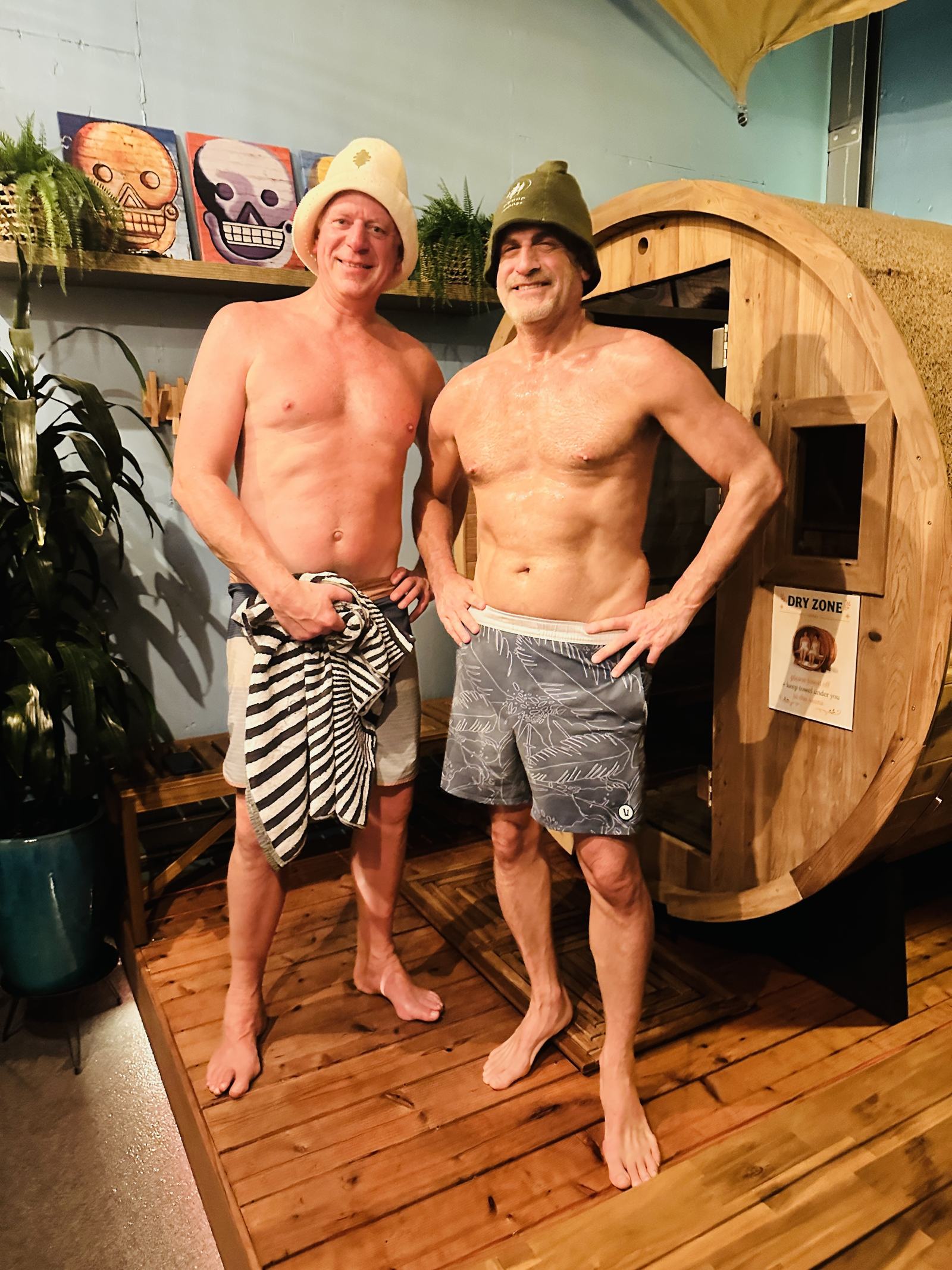 Two people standing in front of the barrel sauna after a session.